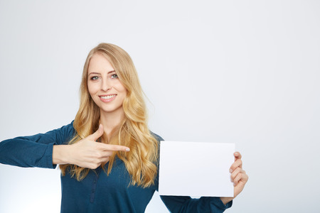 Happy smiling young business woman showing blank signboard, isolated over white backgroundの写真素材