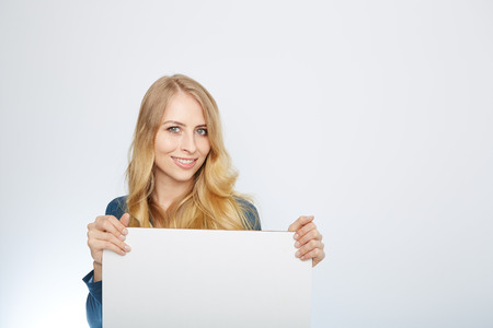 Happy smiling young business woman showing blank signboard, isolated over white backgroundの写真素材