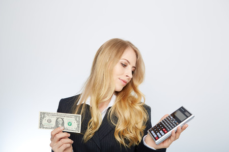 Attractive business woman, wearing a suit and shirt. Holding a dollar and calculatorの写真素材