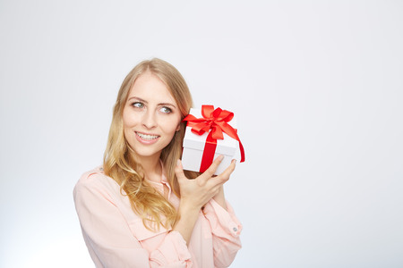 Beauty with gift box. Beautiful young blond hair woman holding gift box and smiling while standing isolated on white backgroundの写真素材