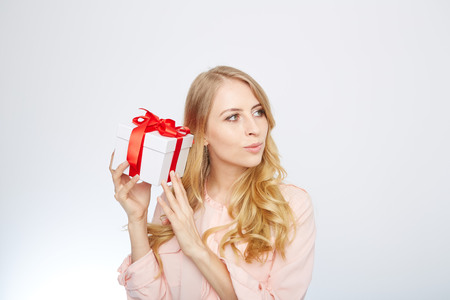 Beauty with gift box. Beautiful young blond hair woman holding gift box and smiling while standing isolated on white backgroundの写真素材