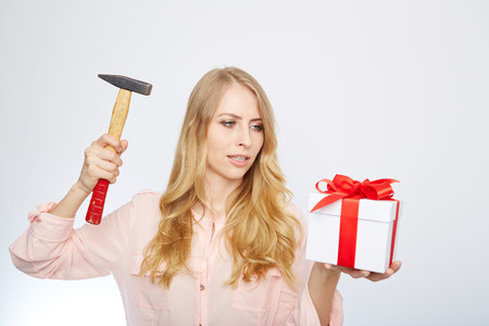 Beauty with gift box an a hammer in her hand.の写真素材
