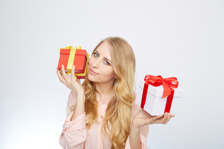 Beauty with gift box. Beautiful young blond hair woman holding gift box and smiling while standing isolated on white backgroundの写真素材