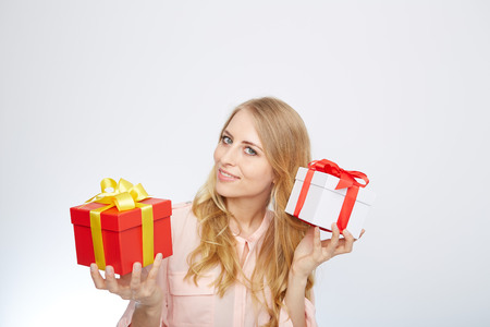 Beauty with gift box. Beautiful young blond hair woman holding gift box and smiling while standing isolated on white backgroundの写真素材