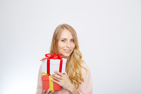 Beauty with gift box. Beautiful young blond hair woman holding gift box and smiling while standing isolated on white backgroundの写真素材