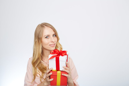 Beauty with gift box. Beautiful young blond hair woman holding gift box and smiling while standing isolated on white backgroundの写真素材