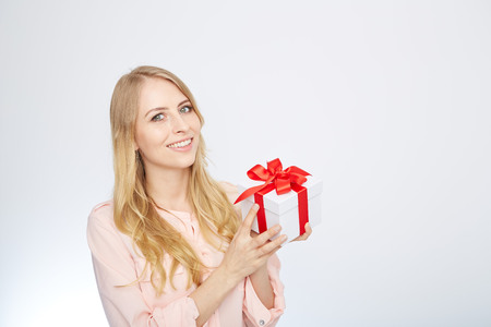 Beauty with gift box. Beautiful young blond hair woman holding gift box and smiling while standing isolated on white backgroundの写真素材