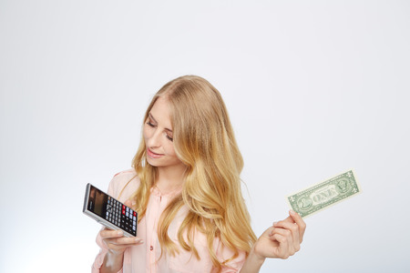 Attractive business woman, wearing a suit and shirt. Holding a dollar and calculatorの写真素材