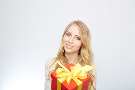 Beauty with gift box. Beautiful young blond hair woman holding gift box and smiling while standing isolated on white backgroundの写真素材