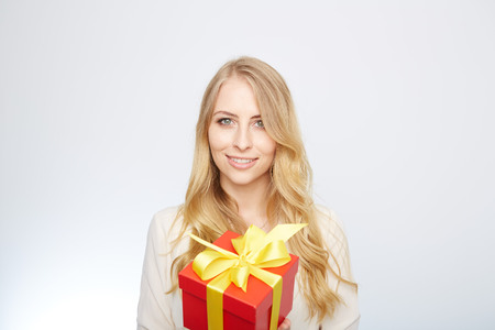 Beauty with gift box. Beautiful young blond hair woman holding gift box and smiling while standing isolated on white backgroundの写真素材