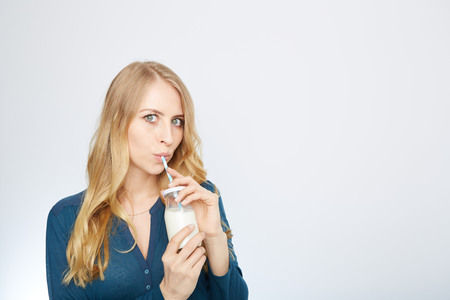 a young woman with a glass of milk. isolated on white.の写真素材
