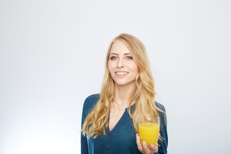 a young woman with a glass of orange juice. isolated on white.の写真素材