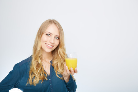 a young woman with a glass of orange juice. isolated on white.の写真素材