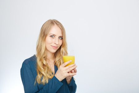 a young woman with a glass of orange juice. isolated on white.の写真素材