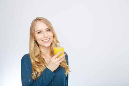 a young woman with a glass of orange juice. isolated on white.の写真素材