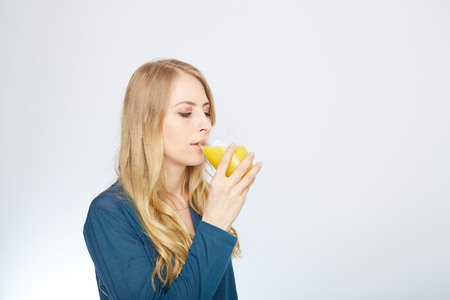 a young woman with a glass of orange juice. isolated on white.の写真素材
