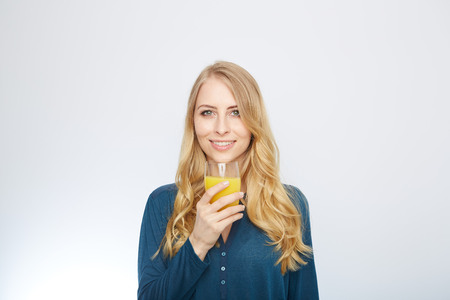 a young woman with a glass of orange juice. isolated on white.の写真素材
