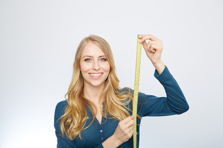 young woman holding a tape measure. isolated on whiteの写真素材