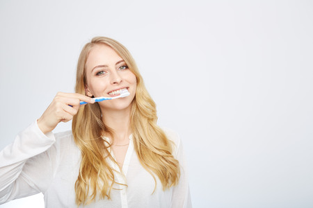 Closeup portrait of a happy beautiful woman brushing her teethの写真素材