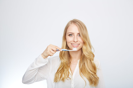 Closeup portrait of a happy beautiful woman brushing her teethの写真素材
