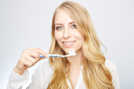 Closeup portrait of a happy beautiful woman brushing her teethの写真素材