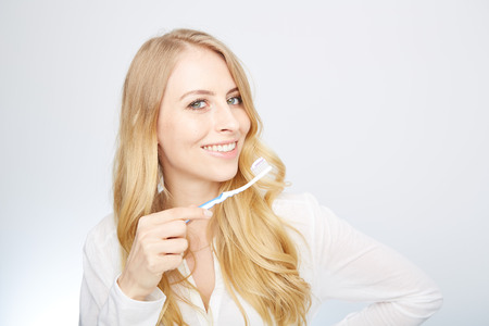 Closeup portrait of a happy beautiful woman brushing her teethの写真素材