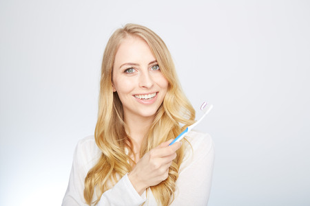 Closeup portrait of a happy beautiful woman brushing her teethの写真素材