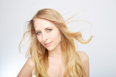 Beautiful woman with long straight blond hair. Fashion model posing at studio.の写真素材