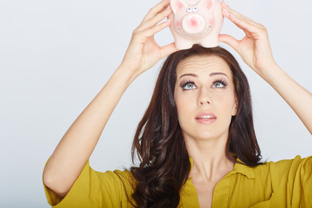 woman looks into a piggy bank. studioの写真素材