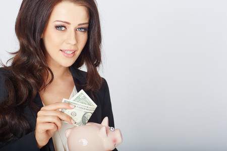 young woman with a dollar and piggy bank in hand. In studioの写真素材