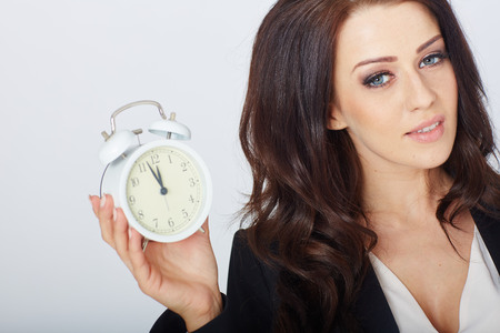 Young businesswoman with an alarm clock. In white studioの写真素材