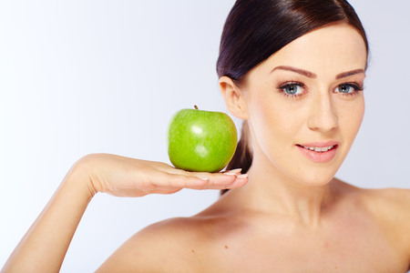 woman with a green apple in a white studioの写真素材