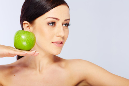 woman with a green apple in a white studioの写真素材