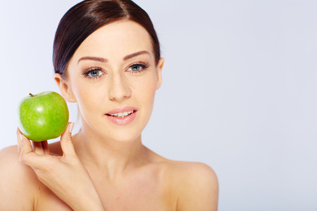 woman with a green apple in a white studioの写真素材