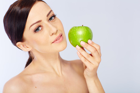 woman with a green apple in a white studioの写真素材