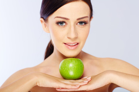 woman with a green apple in a white studioの写真素材