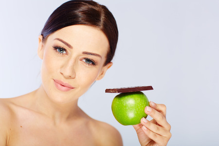 woman with a apple and chocolate in her hand. isolatedの写真素材