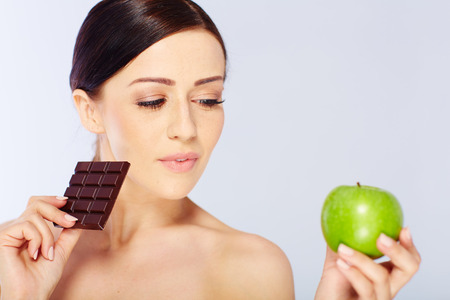 woman with a apple and chocolate in her hand. isolatedの写真素材