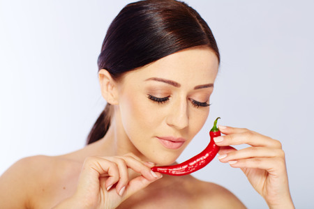 woman with a red chili in a white studioの写真素材