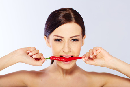 woman with a red chili in a white studioの写真素材