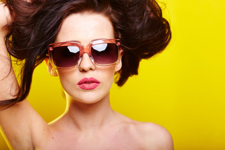 caucasian woman wearing sunglasses over yellow backgroundの写真素材