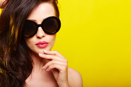 caucasian woman wearing sunglasses over yellow backgroundの写真素材