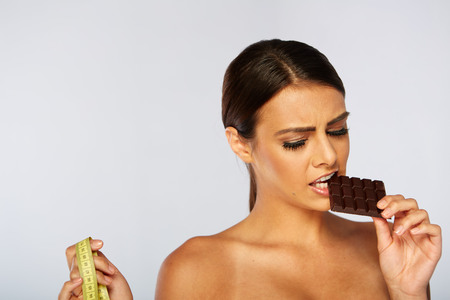 portrait of a brunette young woman with chocolate and tape measureの写真素材