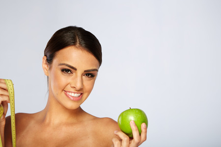 beautiful young woman with green apple and measure tape, isolated on whiteの写真素材