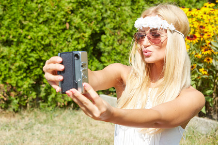 portrait of a smiling young girl making selfie photo in parkの写真素材