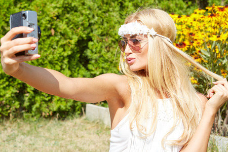 portrait of a smiling young girl making selfie photo in parkの写真素材