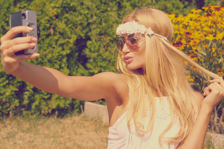 portrait of a smiling young girl making selfie photo in parkの写真素材