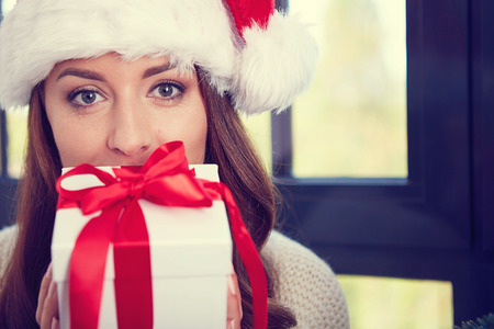 Woman holding a gift for christmas looking in the cameraの写真素材