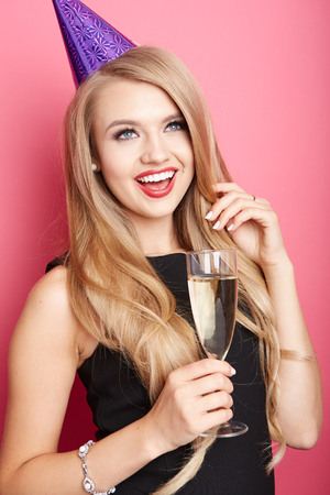 Young celebrating woman black dress, holding a glass of champagne.の写真素材