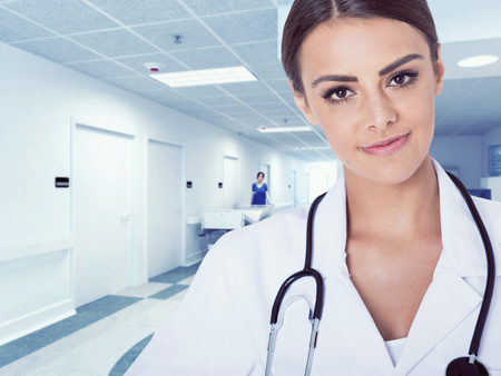 Portrait of woman doctor at hospital corridor,  looking at camera, smiling.の写真素材
